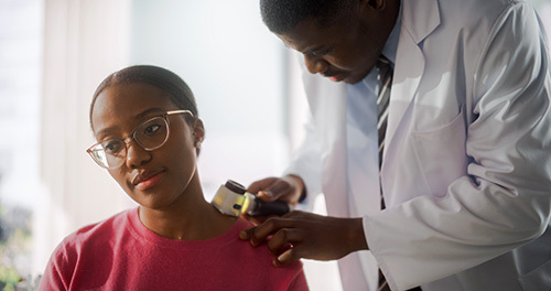 Young African American woman getting her skin checked by a dermatologist